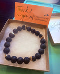 Black beaded bracelet with gold accents in a box with a 'thank you' card.